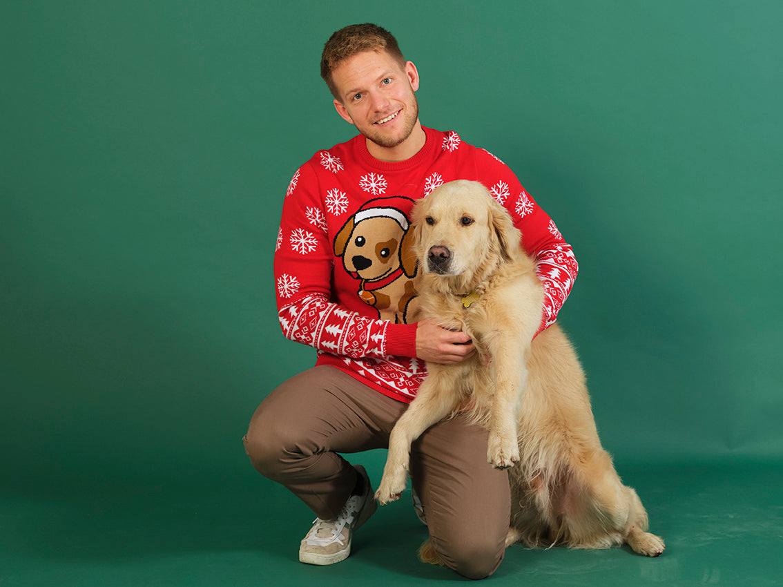 Un uomo con un cane che indossa un maglione di Natale rosso con un cane.